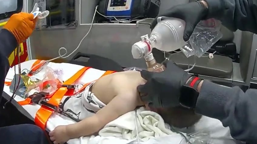 El EMT sostiene el dispositivo respiratorio sobre la boca y las fosas nasales del bebé