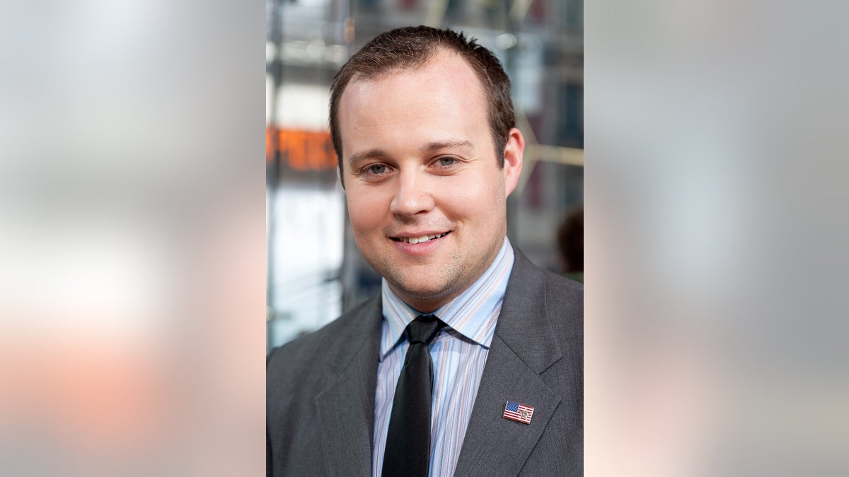 A close-up of Josh Duggar smiling in a suit.