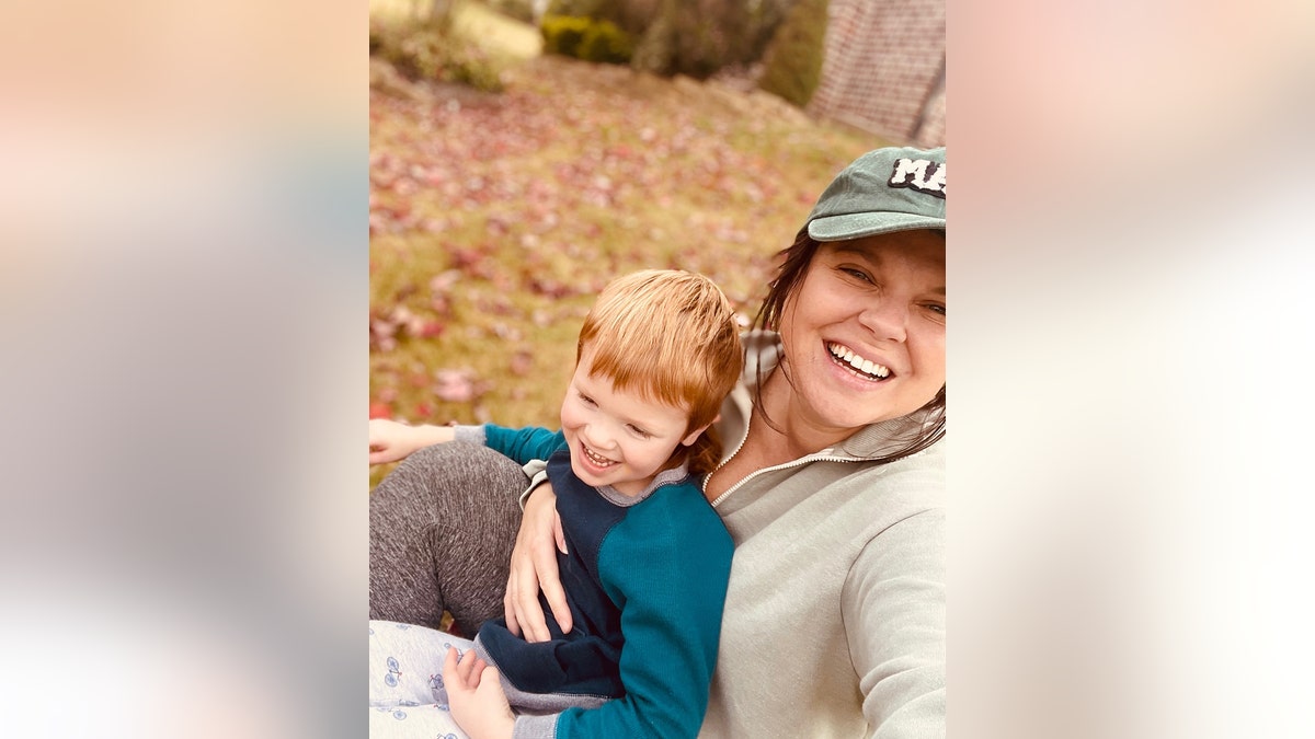 Amy Duggar King taking a selfie and smiling as she takes a selfie with her son.
