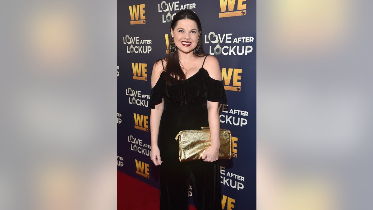 Amy Duggar King wearing an off the shoulder black jumpsuit on the red carpet.