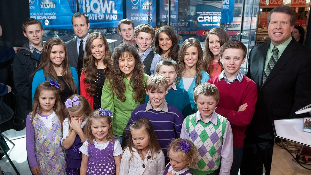 Jim Bob Duggar smiling with his children in a studio.