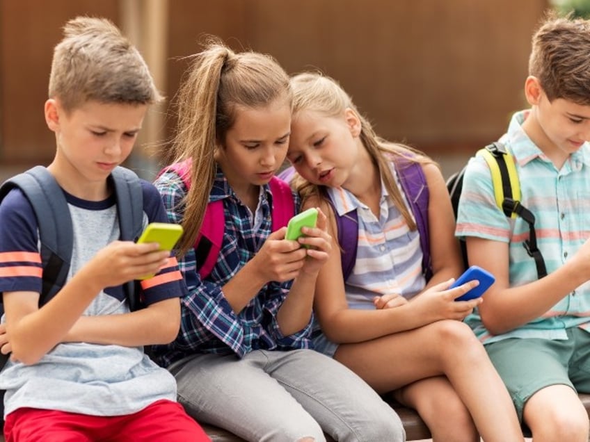 niños en edad escolar usando teléfonos inteligentes