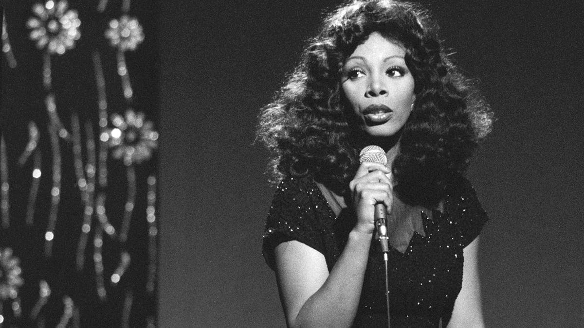Una foto en blanco y negro de Donna Summer sosteniendo un micrófono
