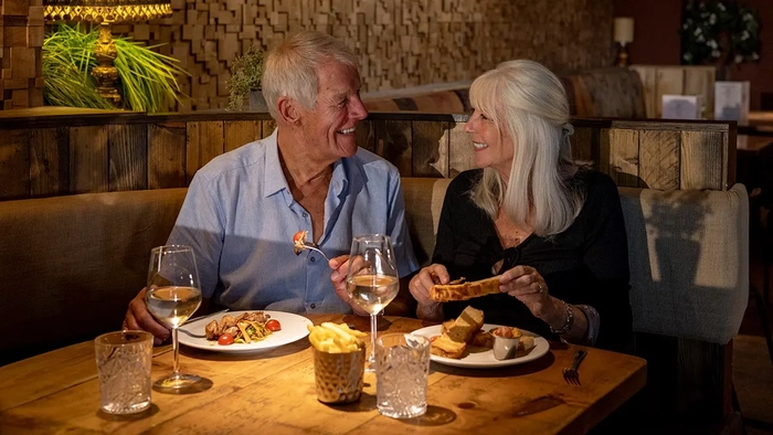 ¿Harto de niños gritones en la cena? Más estadounidenses apoyan las cenas sólo para adultos Una alegre pareja de ancianos sentados uno frente al otro en la mesa de un restaurante disfrutando de la comida