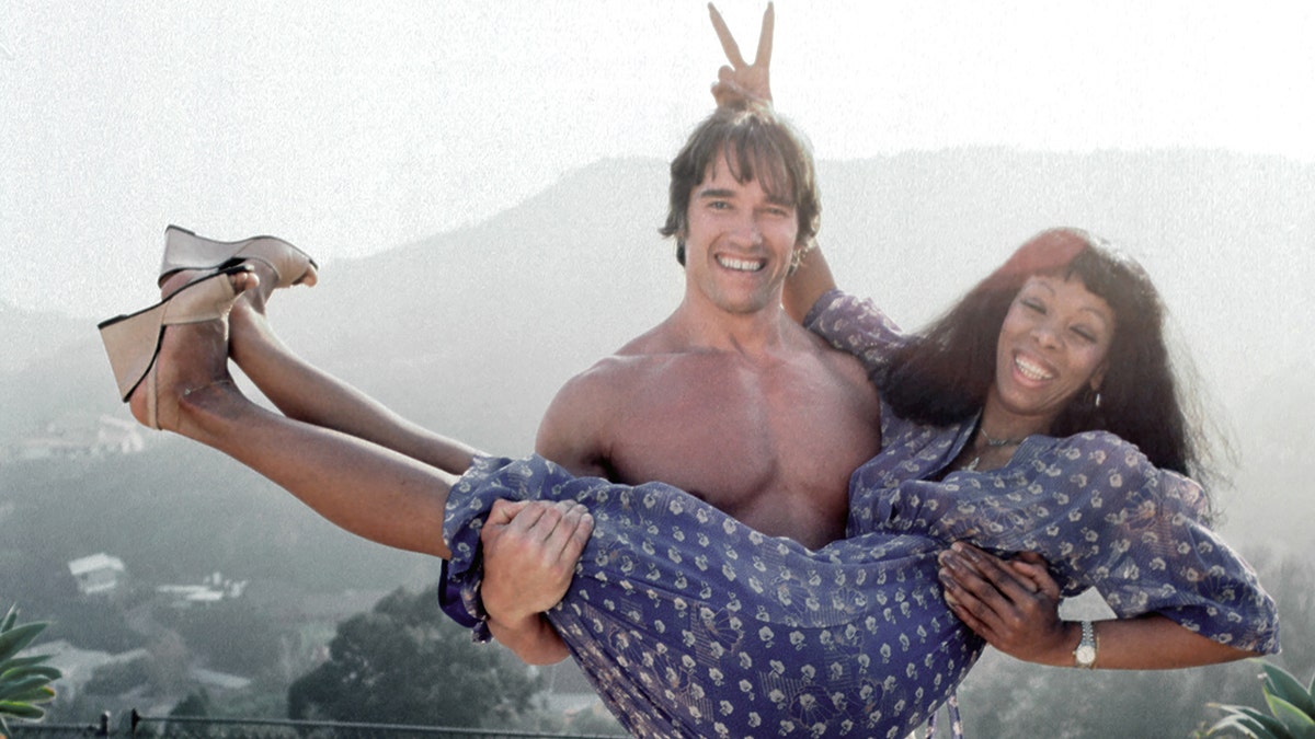 Arnold Schwarzenegger sosteniendo a Donna Summer