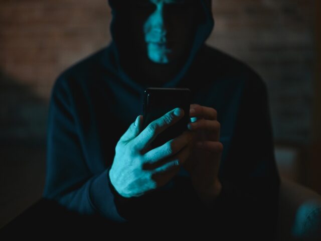 ползучий человек смотрит на свой телефон в темноте