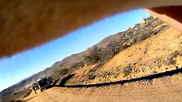 помощник шерифа держит ребенка на руках и спешит к машине скорой помощи