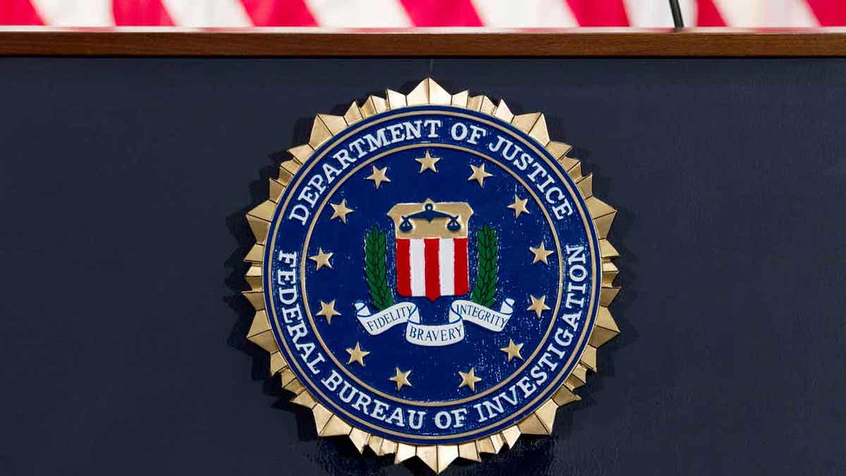 Logotipo y sello del FBI visto debajo de la bandera estadounidense.