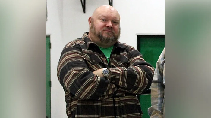 Бывший директор Джереми П. Уильямс стоит со скрещенными руками.