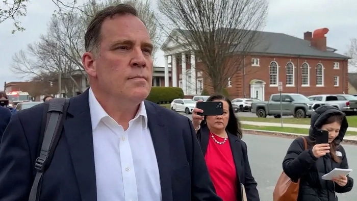 Un antiguo profesor entrando en una sala del tribunal con la prensa detrás de él