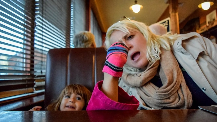 ¿Harto de niños gritones en la cena? Más estadounidenses apoyan las cenas sólo para adultos Niña poniendo el pie en la mesa de un restaurante mientras su madre mira
