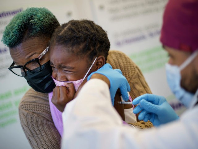Markeata West, left, holds her daughter, Justice, 6, as she receives the Pfizer COVID-19 v