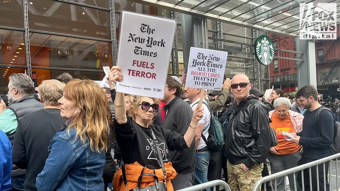 Протестующие требуют, чтобы New York Times отозвала противоречивую статью об "изнасиловании собакой" и уволила Николаса Кристофа Протестующий держит таблички