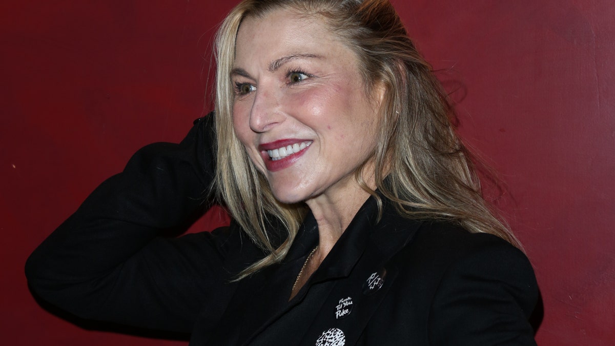 Tatum O'Neal vistiendo un traje negro y sonriendo.