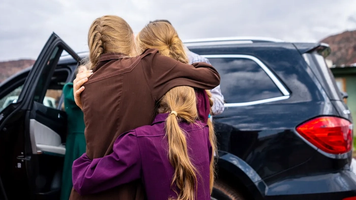 Tres niñas se abrazan antes de que las saquen de la casa de Samuel Bateman