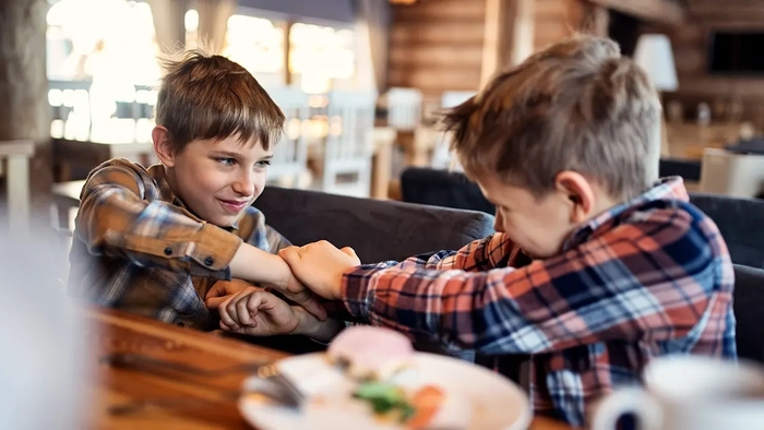 ¿Harto de niños gritones en la cena? Más estadounidenses apoyan las cenas sólo para adultos Dos chicos peleándose y gritando sentados a la mesa de un restaurante