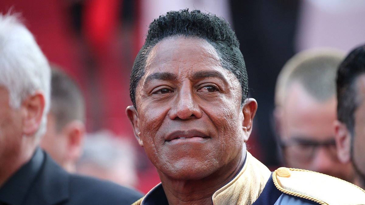 Jermaine Jackson camina por la alfombra roja con un abrigo adornado
