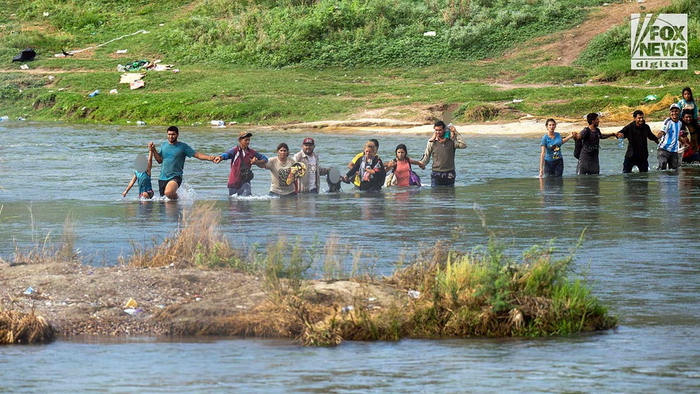 Группа мигрантов, некоторые из которых несут детей, пересекает реку Рио-Гранде в Игл Пасс, штат Техас, 27 сентября 2023 года. Пересечение границы через Игл Пасс продолжает напрягать правоохранительные органы, поскольку каждый день в Соединенные Штаты въезжает беспрецедентное количество мигрантов.
