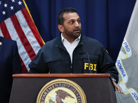 An image of Kash Patel speaking at a podium during a press conference