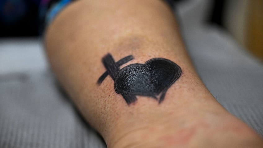 A trafficking victim covers up her brand with a tattoo of a cross and a heart